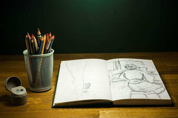 Sketchbook with drawings and colored pencils on a table