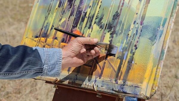 Person painting with watercolors at a wooden table
